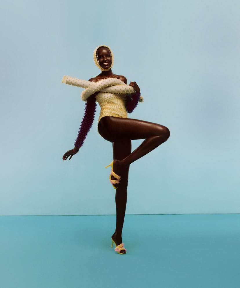 A model wearing a yellow bathing suit with matching swim cap and pool noodle