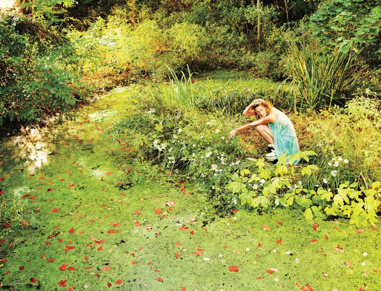 A photograph by Ryan McGinley, styled by Edward Enninful in W July 2013. A model sits in a garden