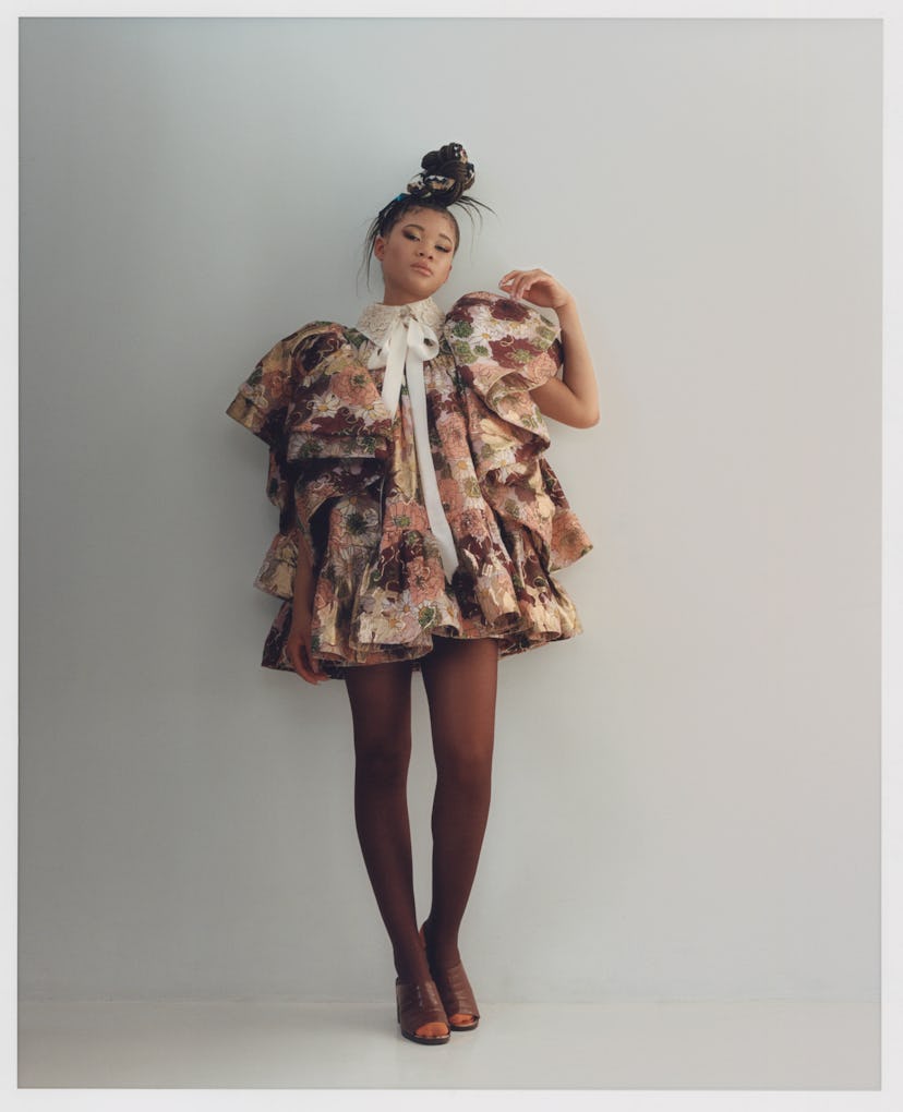 Storm Reid in a floral dress with a white collar and bow posing