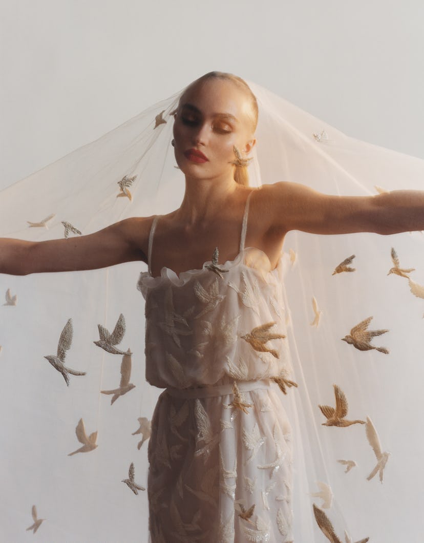 Lily Rose Depp wearing a white gown and veil with embroidered birds